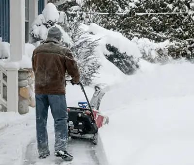 Residential snow removal technician using a snow blower to clear a home driveway and walkway in Fort Wayne, IN